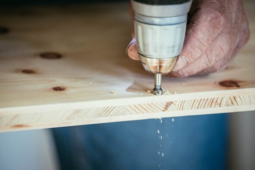 Craftsman is drilling in wood with drilling machine