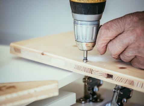 Craftsman is drilling in wood with drilling machine