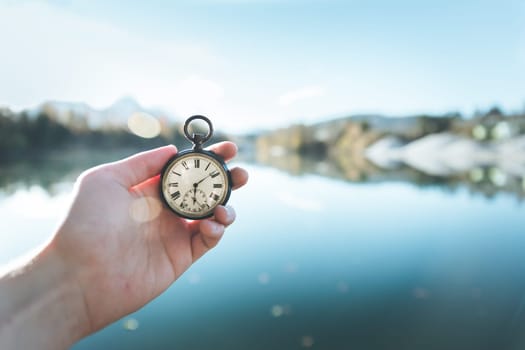 Hand held stop watch outdoors, autumn, blurry blue lake in the background