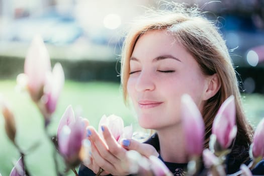 Beautiful girl is smelling magnolia blooms in spring, Salzburg, beauty
