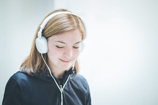 Young cute girl is listening to music with headphones