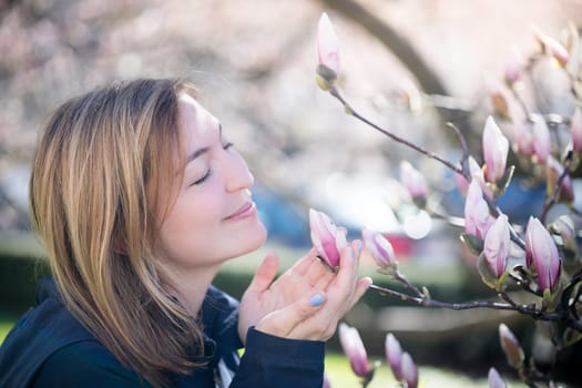 Beautiful girl is smelling magnolia blooms in spring, Salzburg, beauty