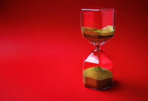 Hourglass on red background with copy space. Time concept.
