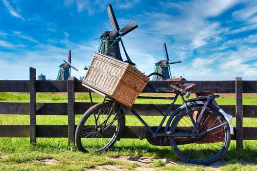 Bicycle with windmill and blue sky background. Scenic countryside landscape close to Amsterdam in Netherlands.