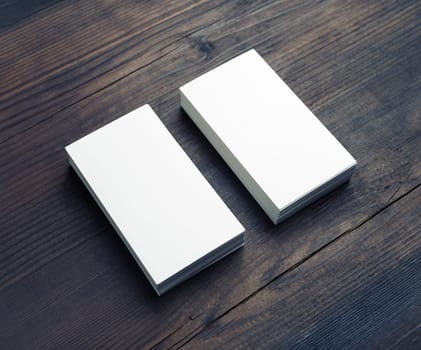 Two blank business cards on wood table background. Branding mockup.