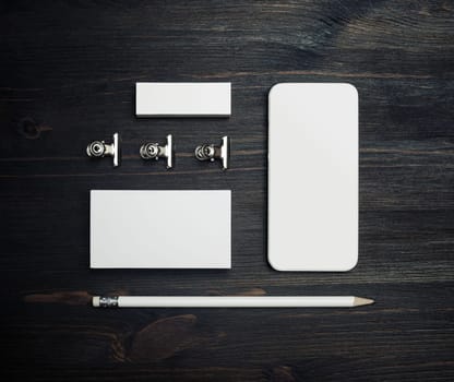 Smartphone and blank stationery: business card, pencil and eraser on wood table background. Top view. Flat lay.