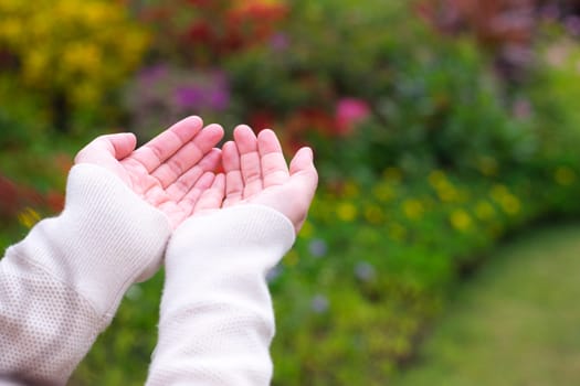 Movement with an empty hand or finger. Empty hand extending the arm to touch something on blurred nature background.