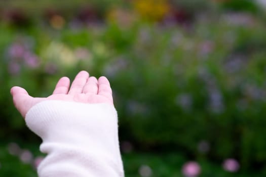 Movement with an empty hand or finger. Empty hand extending the arm to touch something on blurred nature background.