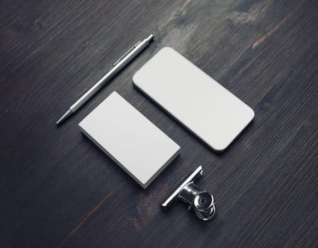 Blank business card, smartphone and pen on wood table background. Responsive design template.