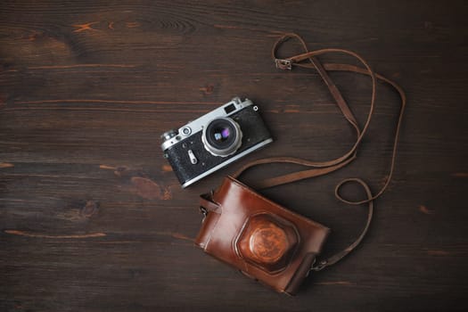 Retro photo camera and holster on wood table background. Flat lay.