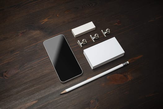 Branding identity template. Blank business card, smartphone, pencil and eraser on wooden background.