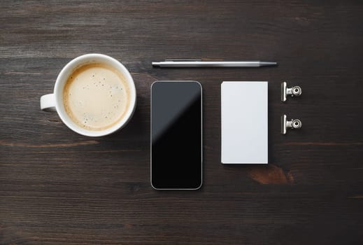Responsive design template. Coffee cup, smartphone, blank business card and pen on wood table background. Flat lay.