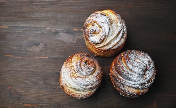 Three delicious sweet buns on wooden background. Flat lay.