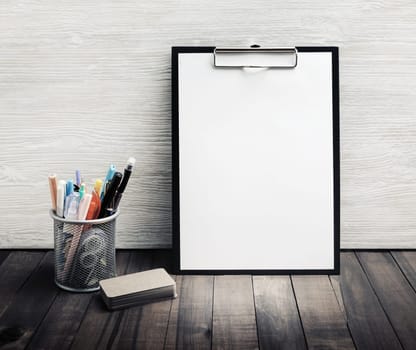 Blank corporate stationery set. Clipboard with blank white sheet of paper, cup holder with pencils and pens, business cards.
