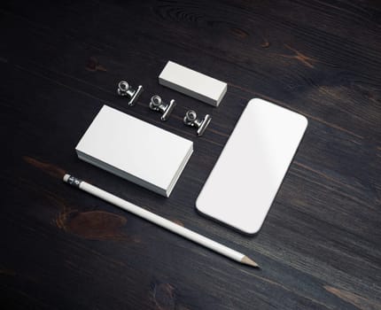 Photo of smartphone, blank business cards, pencil and eraser on wood table background.