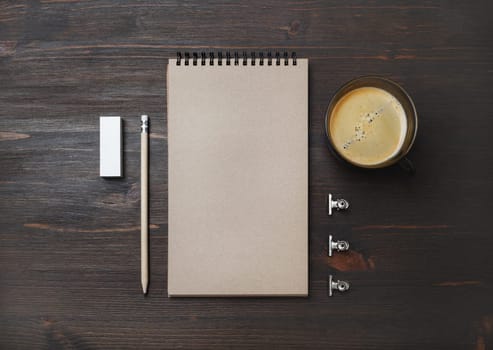 Coffee cup and blank stationery: kraft notebook, pencil and eraser on wood table background. Flat lay.