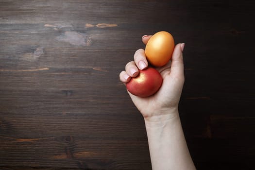 Easter eggs in female hand on wooden background.