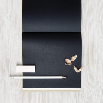 Opened blank black booklet, pencil and eraser on light wood table background. Blank stationery set. Top view. Flat lay.