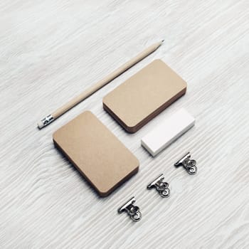 Blank stationery set. Kraft business cards, pencil and eraser on light wooden background. Branding identity. ID mockup.