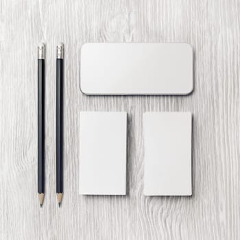 Smartphone, blank business cards and pencils on light wooden background. Branding identity template. Top view. Flat lay.