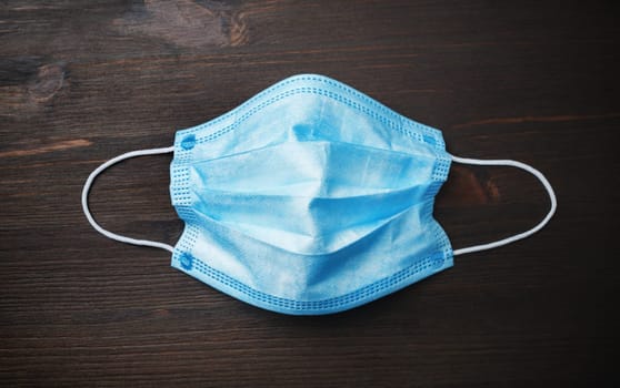 Medical protective mask on wooden background. Flat lay.