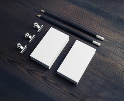 Blank business stationery on wooden background. Blank business cards, pencils and paper clips.
