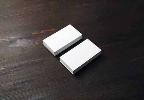 Photo of two blank business cards on wood table background. Branding ID template.
