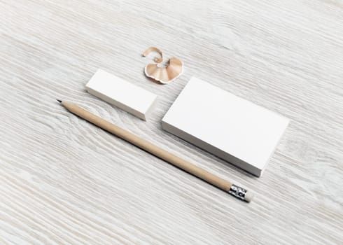 Brand ID mockup. Blank white business card, pencil and eraser on light wooden background.