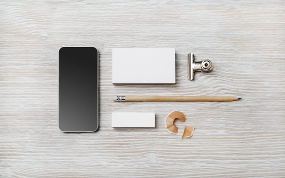 Blank business card, smartphone, pencil and eraser on light wood table background. Branding template. Top view. Flat lay.