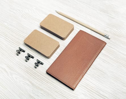Blank notepad, kraft business cards and pencil on light wood table background. Photo of blank stationery set.