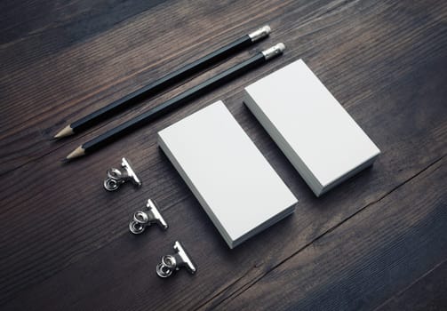 Blank business cards, pencils and paper clips on wood table background. Responsive design template.