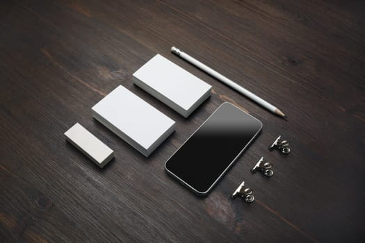 Smartphone and blank stationery: business cards, pencil and eraser on wooden background.