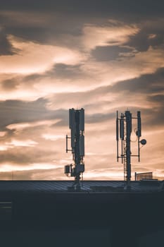 Transmitter antennas in the evening. Orange sky and clouds.