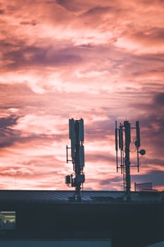Transmitter antennas in the evening. Orange sky and clouds.
