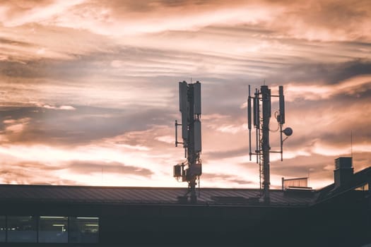 Transmitter antennas in the evening. Orange sky and clouds.