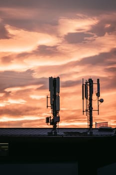 Transmitter antennas in the evening. Orange sky and clouds.