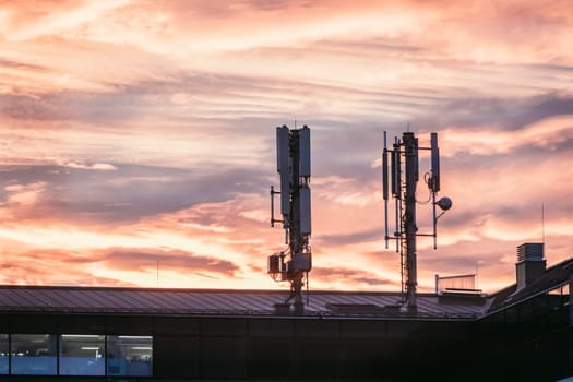 Transmitter antennas in the evening. Orange sky and clouds.