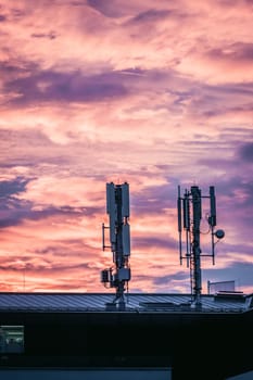 Transmitter antennas in the evening. Orange sky and clouds.