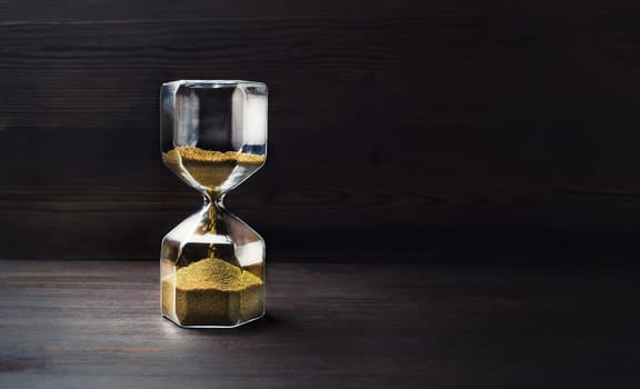 Hourglass on wooden background with copy space. Time Running Out.