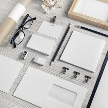 Blank business stationery set on light wood table background.