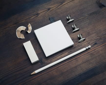 White square notes, pencil and eraser on wood table background. Blank stationery template.