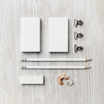 Photo of blank stationery template on light wooden background. Business cards, pencils and eraser. Top view. Flat lay.