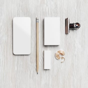 Smartphone, blank business card, pencil and eraser on light wood table background. Branding mock up. Top view. Flat lay.