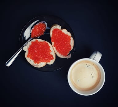 Coffee cup, sandwiches with red caviar and spoon. Flat lay.