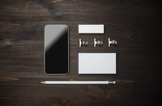 Corporate identity template. Smartphone, blank business card, pencil and eraser on wooden background. Flat lay.