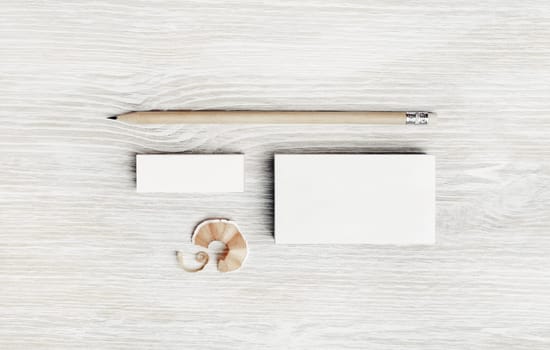 Blank white business card, pencil and eraser on light wood table background. Stationery mock up. Flat lay.