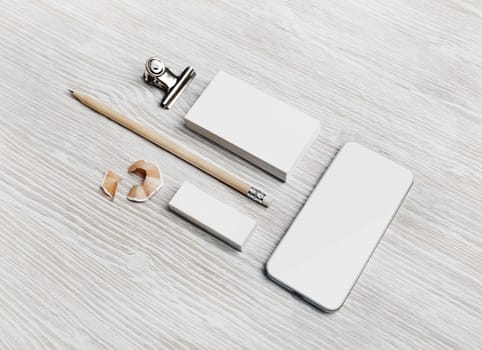 Blank branding template. Smartphone, business card, pencil and eraser on light wood table background.