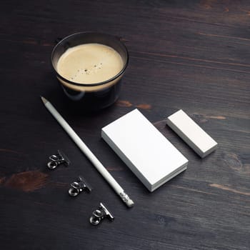 Coffee cup, blank business cards, pencil and eraser on wood table background.