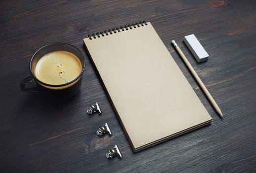 Blank kraft notebook, coffee cup, pencil and eraser on wooden background. Branding mock up.