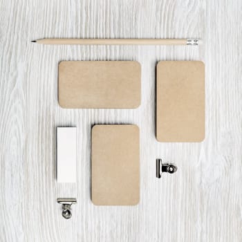 Blank kraft business cards, pencil and eraser on light wood table background. Blank stationery set. Top view. Flat lay.